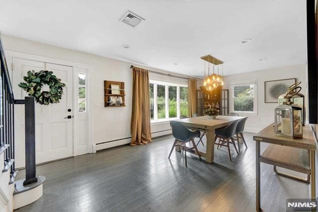 dining space featuring visible vents, baseboard heating, dark wood-style floors, and a chandelier