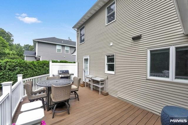 wooden terrace featuring a grill and outdoor dining area