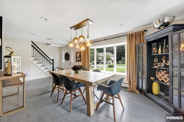 dining room featuring stairway, baseboards, an inviting chandelier, and wood finished floors