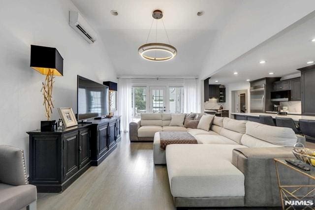 living room with vaulted ceiling, a wall unit AC, recessed lighting, and light wood finished floors