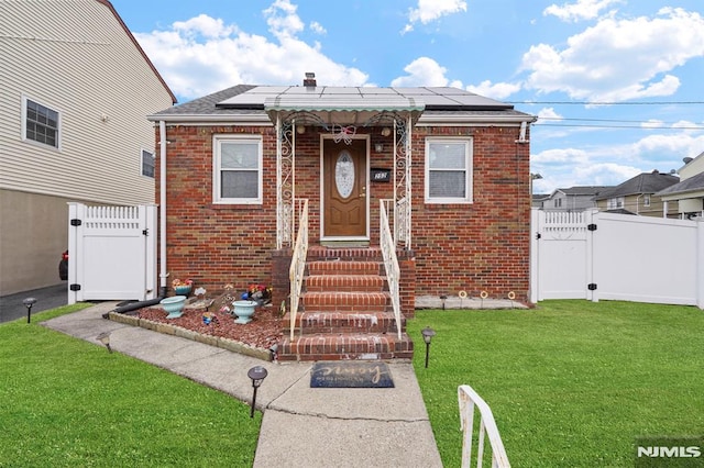 view of front of house featuring a front yard, a gate, brick siding, and fence