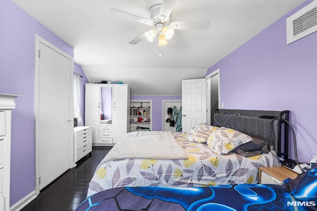 bedroom featuring dark wood-style floors, lofted ceiling, visible vents, and ceiling fan