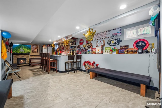 game room featuring recessed lighting, a lit fireplace, and a dry bar