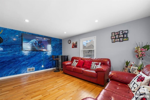 living room with recessed lighting, visible vents, an accent wall, baseboards, and hardwood / wood-style flooring