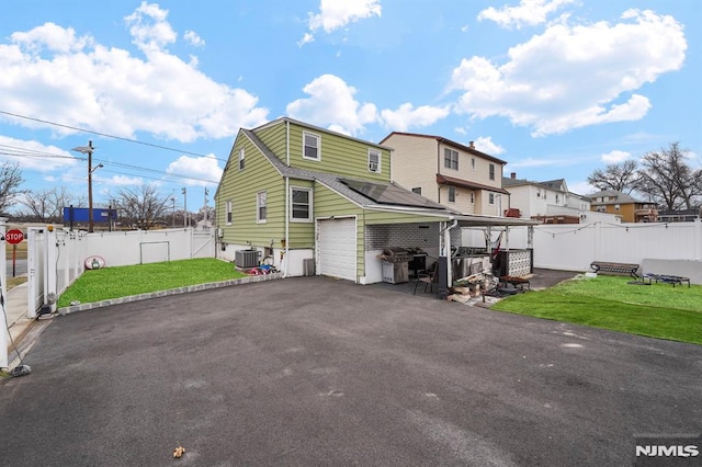 back of property featuring cooling unit, a yard, driveway, and fence private yard