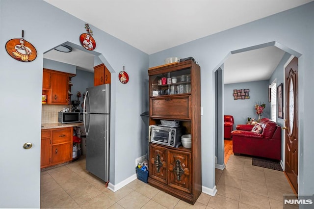 kitchen with arched walkways, open shelves, stainless steel appliances, light countertops, and backsplash