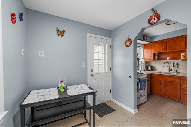 kitchen featuring tasteful backsplash, light countertops, white gas stove, open shelves, and a sink