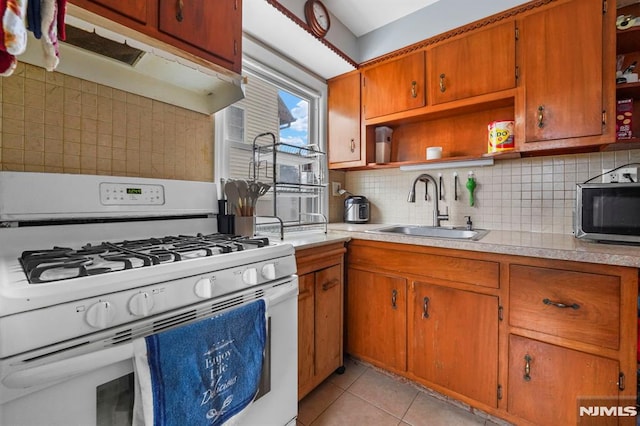 kitchen featuring under cabinet range hood, white range with gas stovetop, a sink, open shelves, and stainless steel microwave