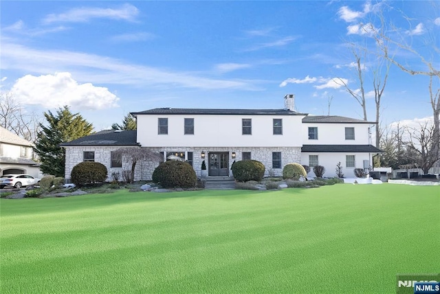 view of front of property with stone siding, a front lawn, a chimney, and stucco siding