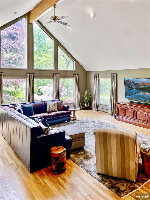 living area featuring ceiling fan, high vaulted ceiling, beamed ceiling, and light wood-style flooring