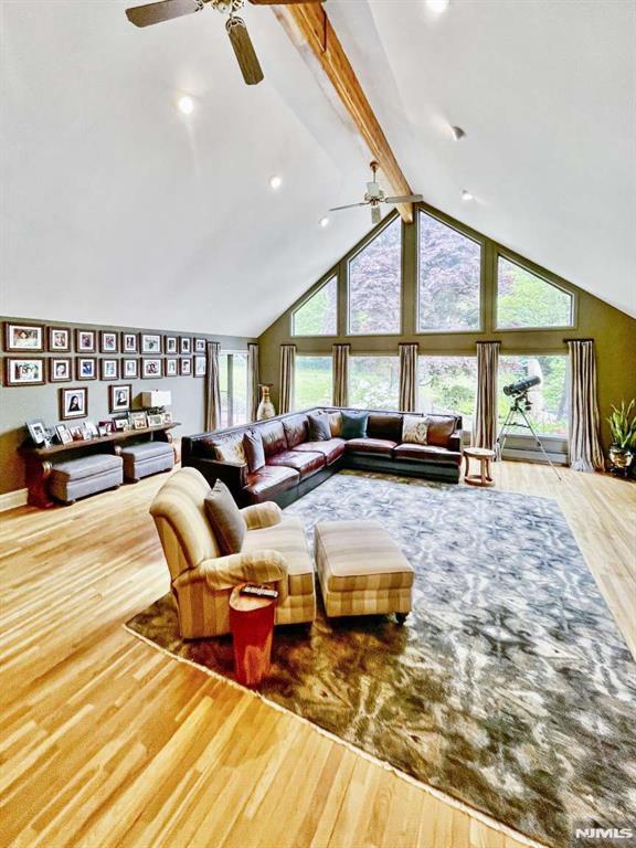 living area featuring high vaulted ceiling, beamed ceiling, plenty of natural light, and wood finished floors