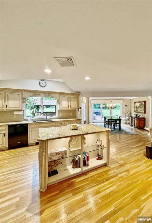 kitchen with light wood finished floors, black dishwasher, visible vents, vaulted ceiling, and a chandelier