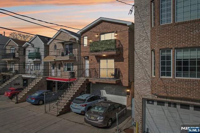 view of front of house with driveway, brick siding, stairway, and an attached garage