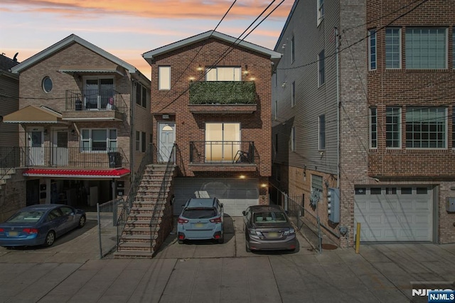 view of front of property featuring stairs, driveway, brick siding, and an attached garage