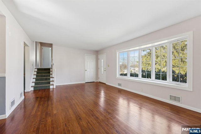 unfurnished living room with visible vents, baseboards, and wood finished floors