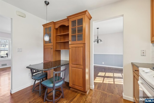 dining room featuring a chandelier, visible vents, baseboards, built in desk, and dark wood finished floors