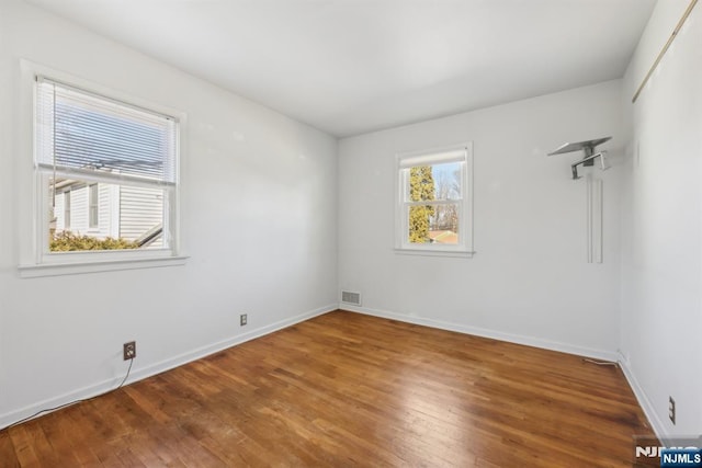 empty room with visible vents, baseboards, and wood finished floors