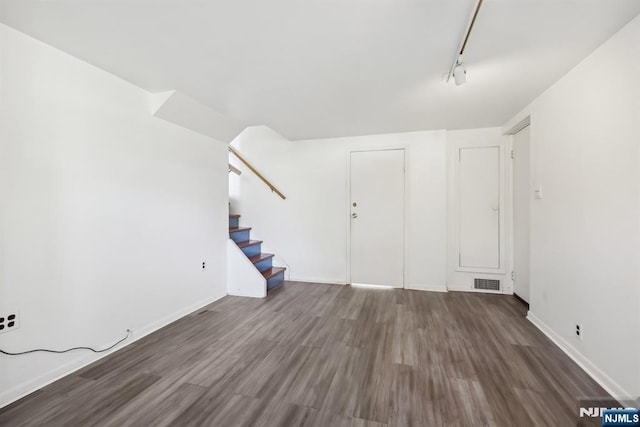 interior space with visible vents, stairway, track lighting, wood finished floors, and baseboards