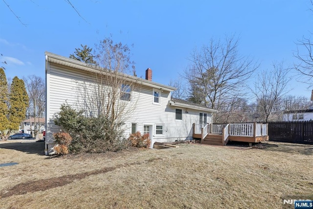 back of house with fence, a chimney, and a wooden deck