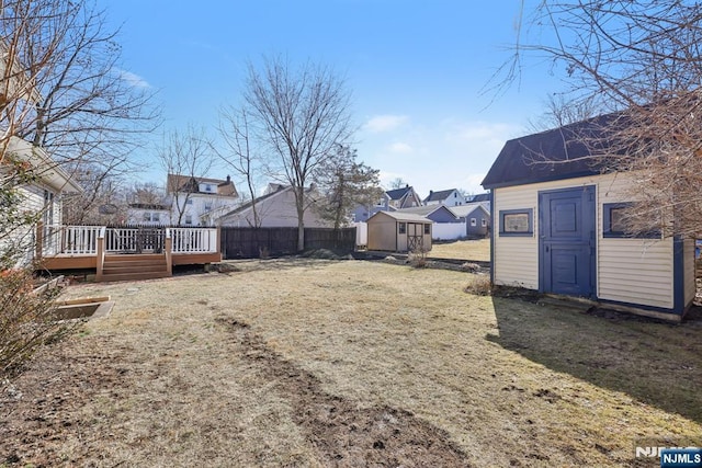 view of yard with fence, a storage unit, an outbuilding, and a wooden deck