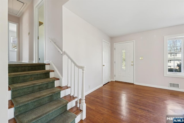 foyer entrance featuring visible vents, stairway, baseboards, and wood finished floors