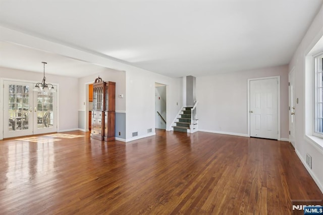 unfurnished living room featuring baseboards, visible vents, stairway, and wood finished floors