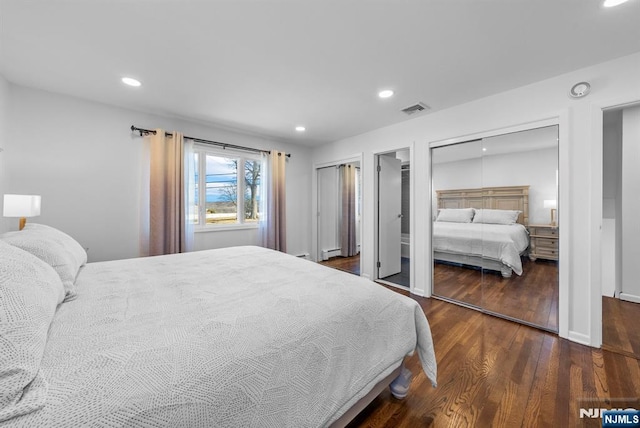 bedroom featuring a baseboard radiator, recessed lighting, dark wood-type flooring, visible vents, and multiple closets