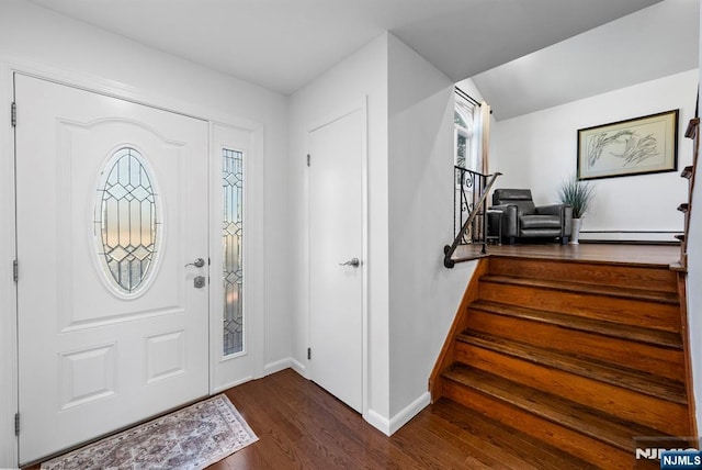 foyer featuring stairway, dark wood-type flooring, a baseboard heating unit, plenty of natural light, and baseboards