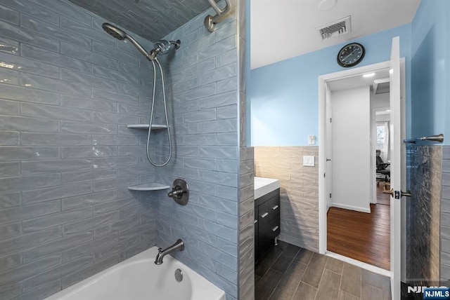 full bathroom featuring visible vents, bathing tub / shower combination, a wainscoted wall, wood tiled floor, and tile walls