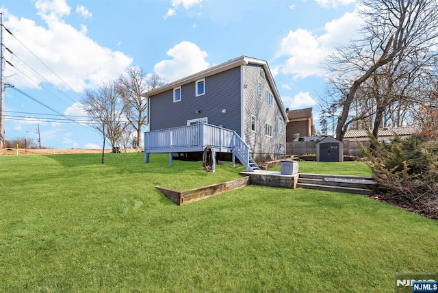 back of house with an outbuilding, a yard, fence, a deck, and a shed