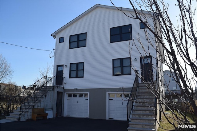 exterior space with aphalt driveway, stairway, an attached garage, and stucco siding