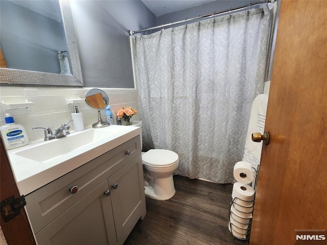 bathroom featuring tile walls, toilet, wainscoting, vanity, and wood finished floors