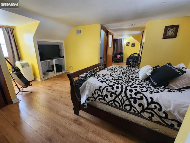 bedroom featuring lofted ceiling, hardwood / wood-style flooring, and visible vents