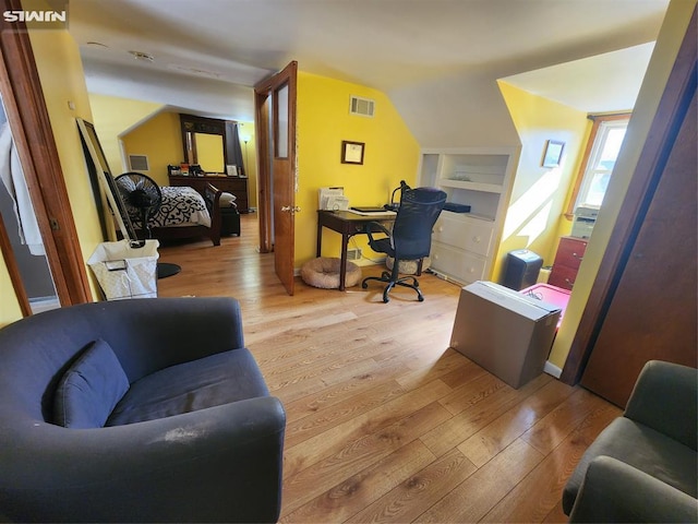 home office with lofted ceiling, wood finished floors, and visible vents