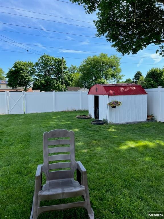 view of yard featuring an outbuilding, a gate, a fenced backyard, and a shed