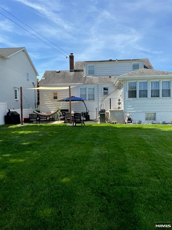 back of house featuring a chimney and a yard