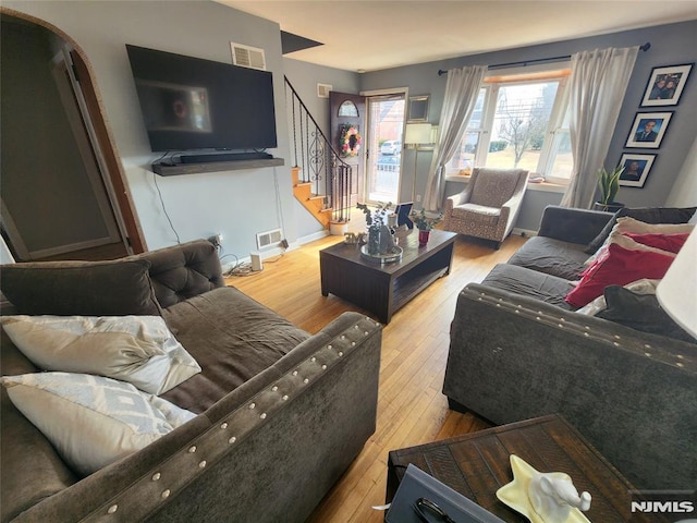 living room featuring hardwood / wood-style flooring, baseboards, stairs, and visible vents