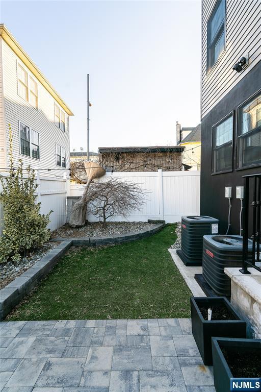 view of yard with cooling unit, fence, and a patio