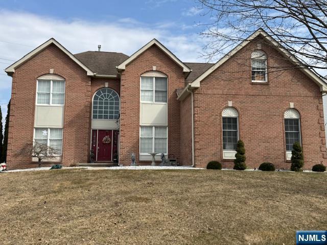 view of front of house featuring brick siding and a front lawn