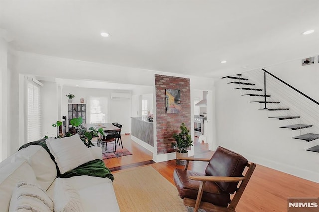 living area featuring recessed lighting, a wall mounted AC, stairway, and wood finished floors