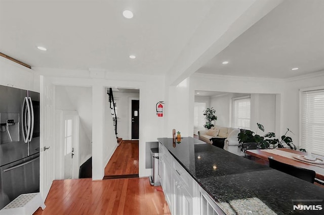 kitchen with dark stone counters, stainless steel fridge, light wood finished floors, and white cabinetry