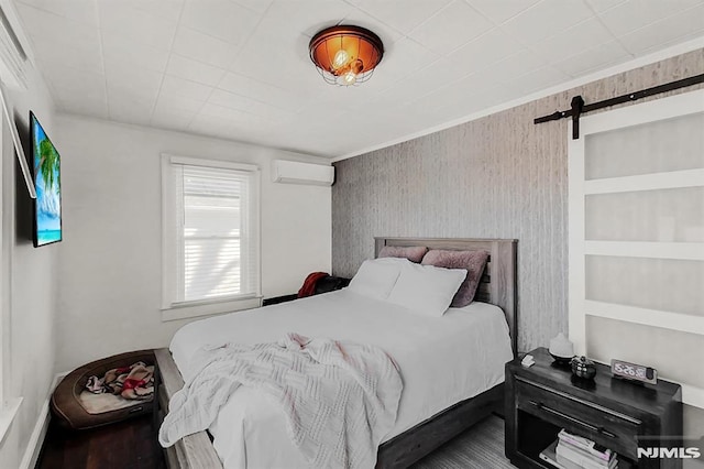 bedroom with a barn door and a wall mounted AC