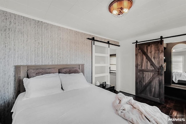 bedroom featuring a barn door and wood finished floors