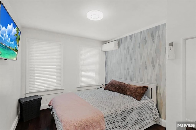 bedroom with baseboards, wood finished floors, and a wall mounted air conditioner