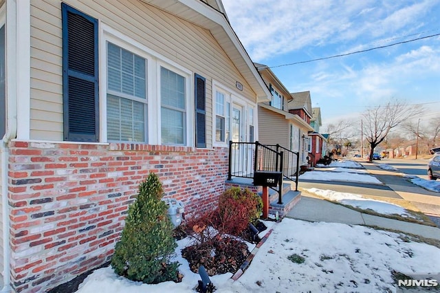 view of snowy exterior with a residential view and brick siding