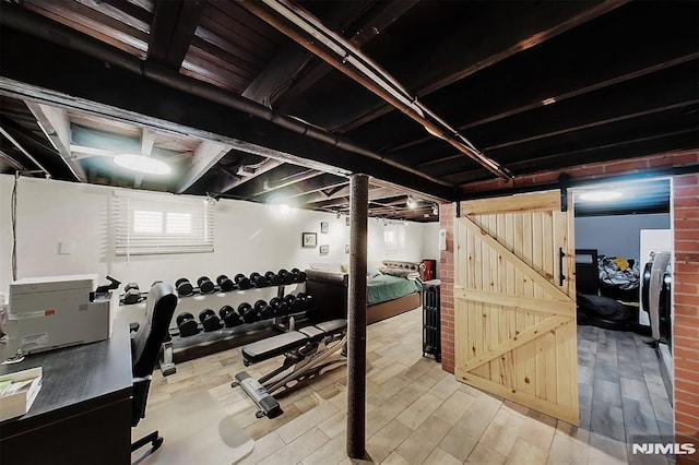 workout room with a barn door, washer / clothes dryer, and wood finished floors