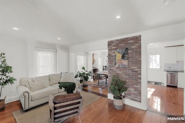 living area featuring baseboards, recessed lighting, wood finished floors, and a healthy amount of sunlight