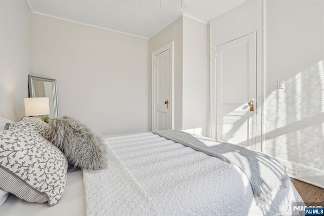 bedroom featuring ornamental molding and wood finished floors