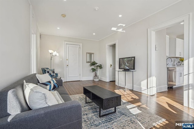 living room with ornamental molding, recessed lighting, baseboards, and wood finished floors