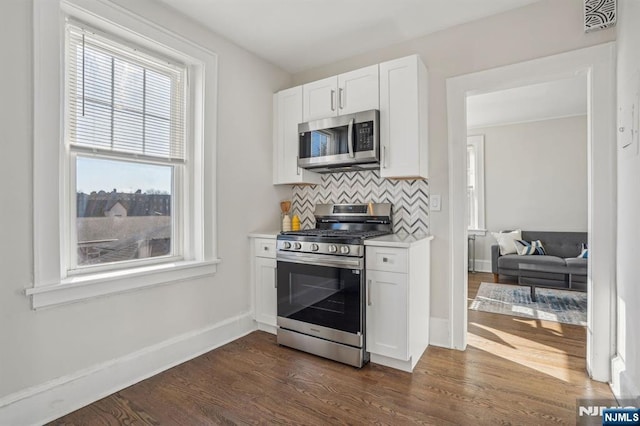 kitchen with stainless steel appliances, white cabinetry, dark wood finished floors, and tasteful backsplash